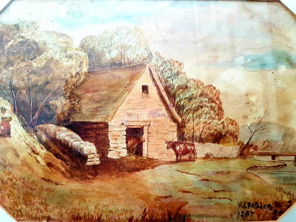 Watercolour painting by Walter Pasley dated 1887.  It depicts a pastoral scene of green countryside with a stone barn and two cows, beside a river.  A female figure is walking down the slope beside the barn.