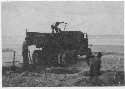 Three men shovelling mineral sand onto a truck on Main Beach, North Stradbroke Island. The North Stradbroke Island sandmining industry started soon after World War 2 (1939-1945). It began on the east-facing Main Beach where wave action exposed seams of the black, mineral-bearing sand. 