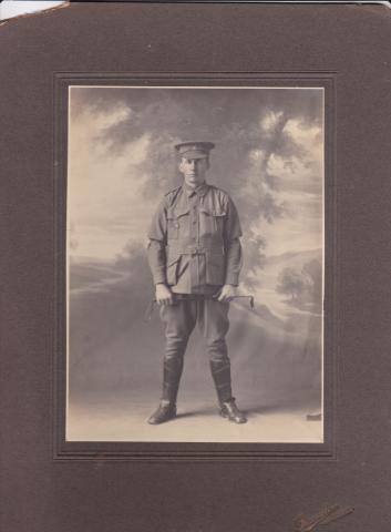 Black and white photograph of John Gordon Leslie (Gordon) Campbell in his Light Horse Uniform, taken in a studio.  He wears a cap instead of the slouch hat, military tunic, riding breeches, leather leggings and boots, and carries a riding crop.