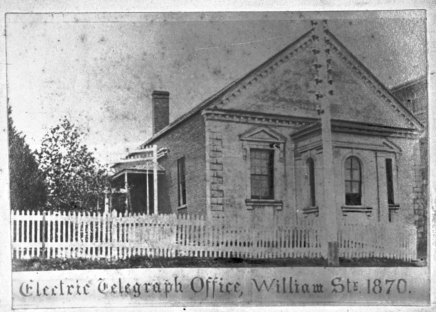 The Electric Telegraph Office brick building with white picket fence in front.