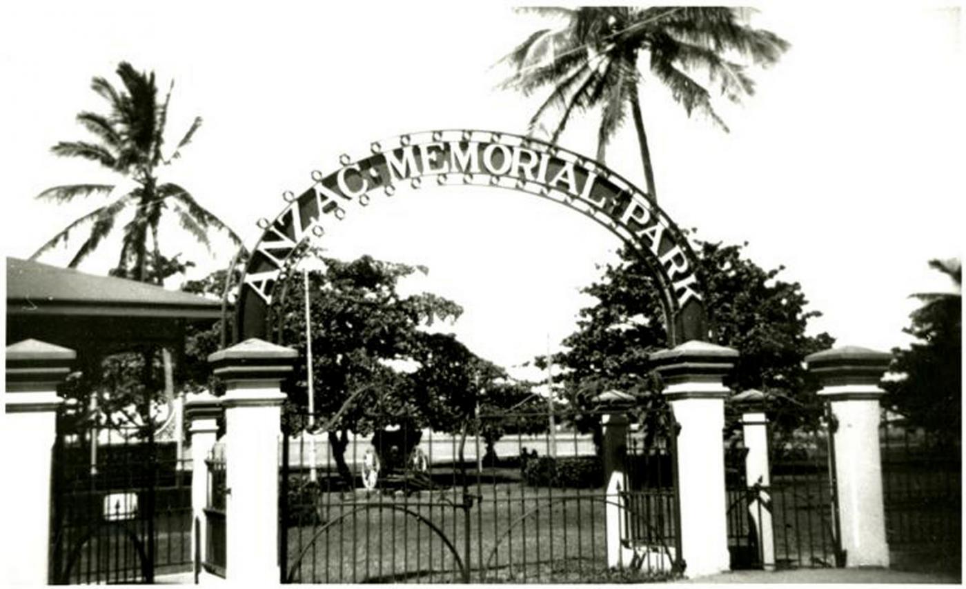 View of a gate marking the entry to a large park, a sign on the gate reads "Anzac Memorial Park"