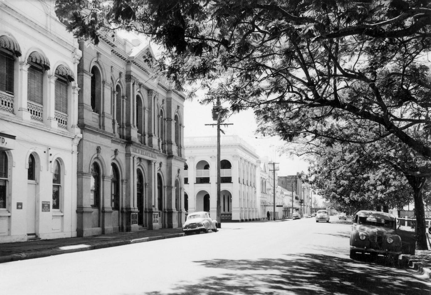Showing the tree lined street and solid stone facade of Quay Street, Rockhampton