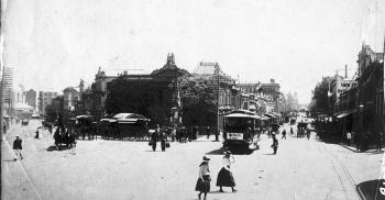 View of a historic street scene on the corner of two busy streets in early 1900s Brisbane